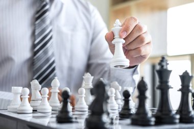 Oyunculu siyah-beyaz satranç, rakipte satranç figürünü hareket ettirmeyi düşünen iş adamının elleri ve başarı için strateji planlama..