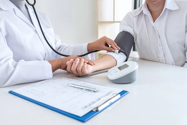 Doctor using stethoscope checking measuring arterial blood pressure on arm to a patient in the hospital, healthcare and medical concept.
