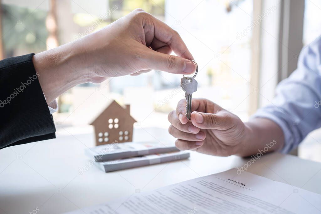 Sale purchase contract to buy a house, Real estate agent are presenting home loan and giving keys to customer after signing contract to buy house with approved property application form.