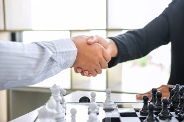 Oyuncu, İşadamı ve İş Kadını ile siyah ve beyaz satranç, rakip oyuncu ve planlama ile rekabetteki satranç figürlerini hareket ettirmek için düşünme stratejisinin ardı ardına el sıkışıyor.