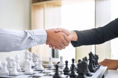 Oyuncu, İşadamı ve İş Kadını ile siyah ve beyaz satranç, rakip oyuncu ve planlama ile rekabetteki satranç figürlerini hareket ettirmek için düşünme stratejisinin ardı ardına el sıkışıyor.