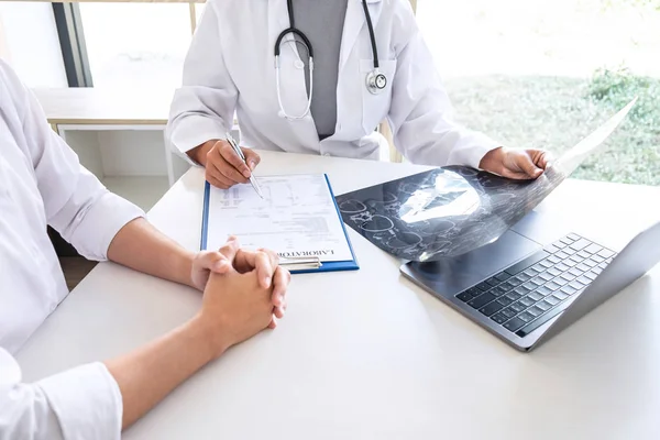 Doctor holding and looking at x-ray film examining at brain by ct scan of patient and analyze result while discussing explaining problem of medical.
