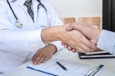 Doktor ve hasta hastanede iyi ve başarılı bir tedavinin ardından el sıkışıyor, sağlık ve yardım kavramı.