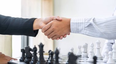 Oyuncu, İşadamı ve İş Kadını ile siyah ve beyaz satranç, rakip oyuncu ve planlama ile rekabetteki satranç figürlerini hareket ettirmek için düşünme stratejisinin ardı ardına el sıkışıyor.