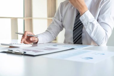 Bilgisayarda grafik üzerinde çalışan genç iş adamı ya da muhasebeci, veri istatistiklerini ve hesap makinesini analiz ederek pazarlama araştırma planlama raporunu sunar..