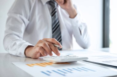 Bilgisayarda grafik üzerinde çalışan genç iş adamı ya da muhasebeci, veri istatistiklerini ve hesap makinesini analiz ederek pazarlama araştırma planlama raporunu sunar..