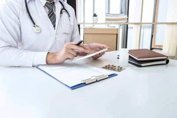 診療所や医療用聴診器でデジタルタブレットを扱う医師 机の上にクリップボード上の薬 — ストック写真