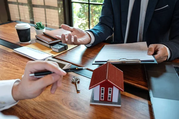 Sale purchase contract to buy a house, Real estate agent are presenting home loan and giving keys to customer after signing contract to buy house with approved property application form.