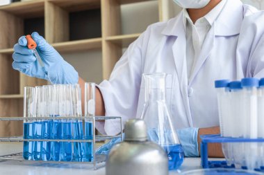 Laboratuvarda virüs ve aşı antiretroviral koronavirüs hakkında çalışan kadın araştırmacı ya da doktor test tüpleri ve mavi sıvı çözeltisi ile araştırma yapıyor..