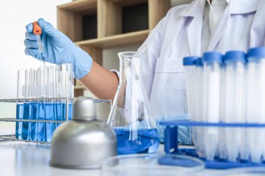 Laboratuvarda virüs ve aşı antiretroviral koronavirüs hakkında çalışan kadın araştırmacı ya da doktor test tüpleri ve mavi sıvı çözeltisi ile araştırma yapıyor..