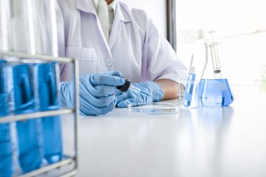 Laboratuvarda virüs ve aşı antiretroviral koronavirüs hakkında çalışan kadın araştırmacı ya da doktor test tüpleri ve mavi sıvı çözeltisi ile araştırma yapıyor..