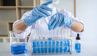 Laboratuvarda virüs ve aşı antiretroviral koronavirüs hakkında çalışan kadın araştırmacı ya da doktor test tüpleri ve mavi sıvı çözeltisi ile araştırma yapıyor..