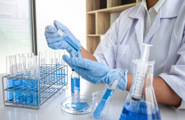 Laboratuvarda virüs ve aşı antiretroviral koronavirüs hakkında çalışan kadın araştırmacı ya da doktor test tüpleri ve mavi sıvı çözeltisi ile araştırma yapıyor..