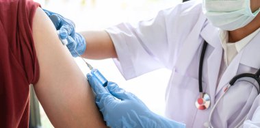 Doktor iğneyle hastaya aşı yapıyor. Grip aşısı için koluna bağışıklık aşısı yaptırıyor. Salgına karşı koronavirüs koruyucu..