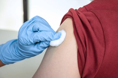 Doktor iğneyle hastaya aşı yapıyor. Grip aşısı için koluna bağışıklık aşısı yaptırıyor. Salgına karşı koronavirüs koruyucu..