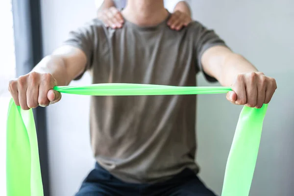 Doktor ya da fizyoterapist, sporcu erkek hastaların yaralı kollarını tedavi ediyor, esneme ve egzersiz yapıyor, klinikte rehabilitasyon tedavisi uyguluyor..