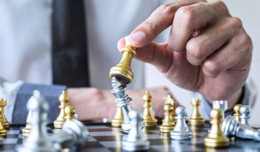 Oyunculu altın ve gümüş satranç, iş adamının elleri satranç figürlerini başarıya ulaşmak için strateji planlama yarışında hareket ettiriyor..