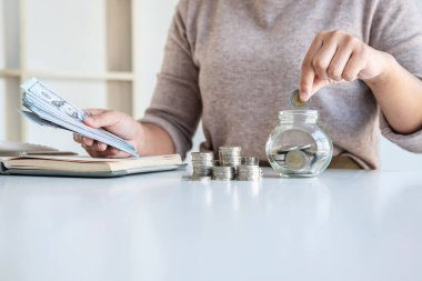 Genç bir kadın para kasası planlamasına para yatırıyor. Strateji ve planlama için para biriktiriyor. Seyahat, eğitim, ev ve emeklilik fonu..