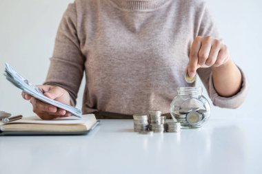 Genç bir kadın para kasası planlamasına para yatırıyor. Strateji ve planlama için para biriktiriyor. Seyahat, eğitim, ev ve emeklilik fonu..