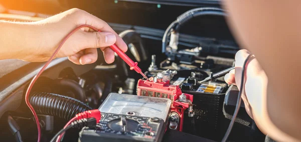 Otomobil tamir servisinde motor otomobili kontrol eden tamirci ve çeşitli değerleri ölçmek ve analiz etmek için dijital çoklu metre test pili, Servis ve Bakım araba pili kontrolü.