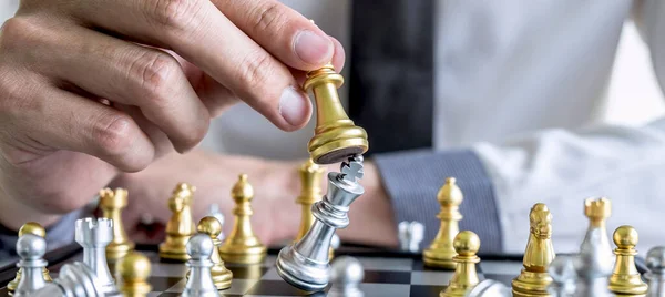 Gold and silver chess with player, Hands of businessman moving chess figure in competition to planning strategy to success play for win.