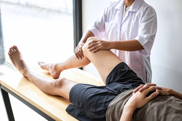 女性理疗师检查男性患者受伤腿的治疗情况 并在临床上练习康复治疗疼痛 — 图库照片