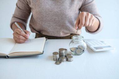 Genç bir kadın para kasası planlamasına para yatırıyor. Strateji ve planlama için para biriktiriyor. Seyahat, eğitim, ev ve emeklilik fonu..