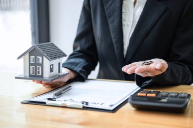 Emlakçı, ev modeli ve anahtarı olan müşterileri için ev sigortası sözleşmesi imzalama sözleşmesi imzalıyor..