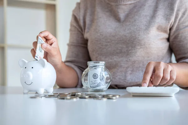 Young woman putting money into piggy bank planning growing saving to strategy and calculating with money box for future plan fund of travel, education, home and retirement.