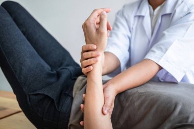 Kadın fizyoterapist, erkek sporcunun yaralı kolunu tedavi ediyor, esneme ve egzersiz yapıyor, klinikte rehabilitasyon tedavisi uyguluyor..