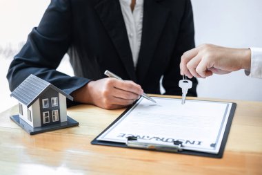 Ev Sigortası ve Gayrimenkul Yatırım Konsepti. Satış acentesinin yeni bir müşteriye ev anahtarı vermesi. Onaylanmış emlak başvuru formu ile anlaşma yaptıktan sonra..