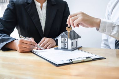 Ev Sigortası ve Gayrimenkul Yatırım Konsepti. Satış acentesinin yeni bir müşteriye ev anahtarı vermesi. Onaylanmış emlak başvuru formu ile anlaşma yaptıktan sonra..