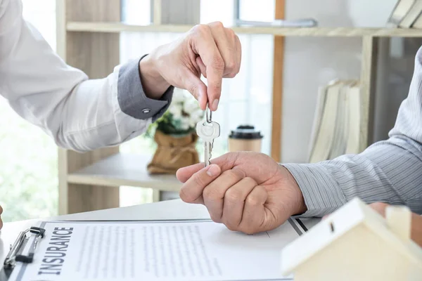 不動産業者は 住宅ローンを提示し 承認された不動産申請書 保険ホームコンセプトで家を購入する契約を締結した後 顧客に鍵を送信しています — ストック写真