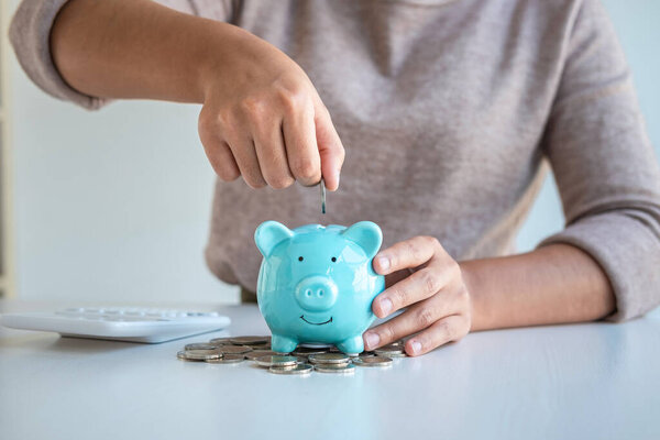 Young woman putting coins into piggy bank planning growing saving to strategy with money box for future plan fund of travel, education, home and retirement.