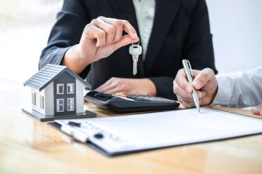 Ev Sigortası ve Gayrimenkul Yatırım Konsepti. Satış acentesinin yeni bir müşteriye ev anahtarı vermesi. Onaylanmış emlak başvuru formu ile anlaşma yaptıktan sonra..