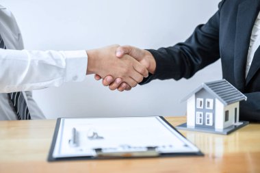Emlakçı, iyi bir anlaşma yaptıktan sonra el sıkışıyor ve ev veriyor. Onaylanmış başvuru formu ile ev almak için kontrat imzaladıktan sonra müşterinin anahtarları..