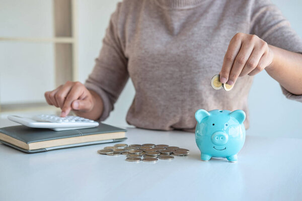 Young woman putting coins into piggy bank planning growing saving to strategy with money box for future plan fund of travel, education, home and retirement.