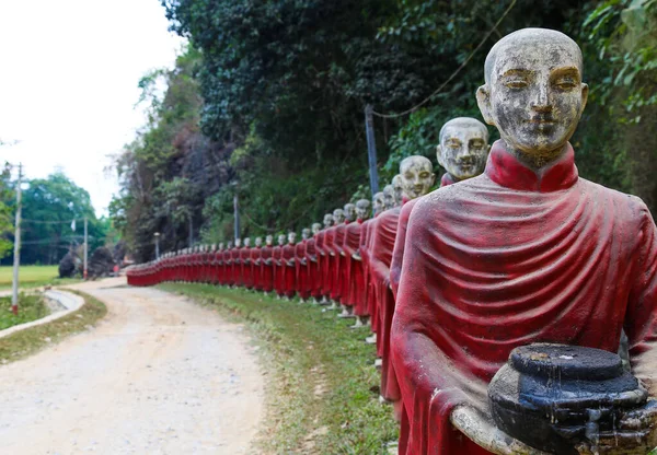 Statues of monks in robes collecting alms in the public park in Myanmar