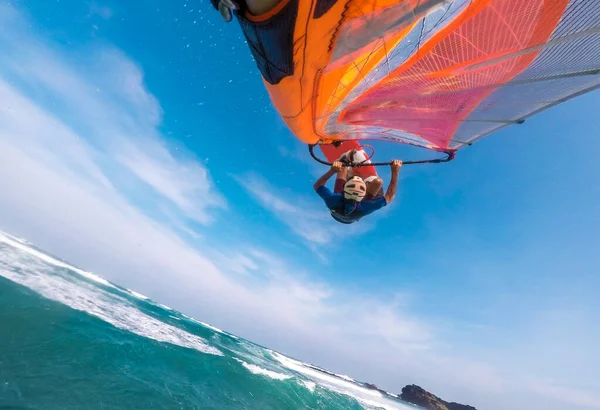 a windsurfer with a bright sail and board does the trick jump in the air over the tropical sea