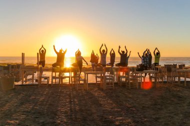 Gün batımında grup yogası.