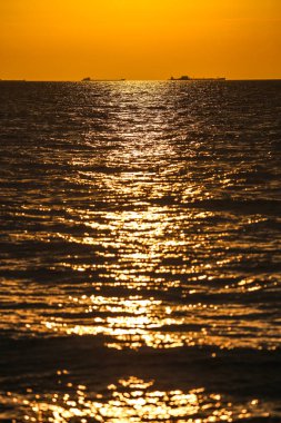 Gün batımında ufukta kargo gemileri beliriyor.