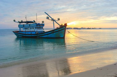 Gün batımında ıssız bir sahilde balıkçı teknesi.