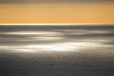 Kurşun bulutlar ve güneş ışınları okyanusun üzerinden geçiyor.