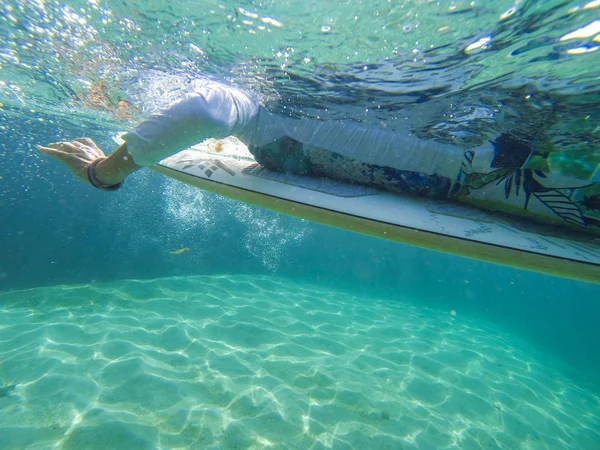 Foto de uma menina em uma prancha de surf debaixo da água — Fotografia de Stock