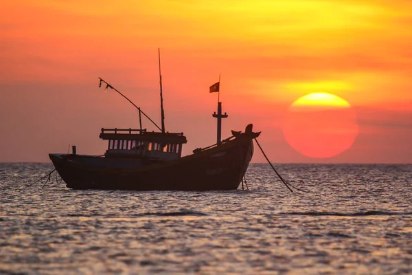 Barco de pesca no fundo de um pôr do sol enorme — Fotografia de Stock