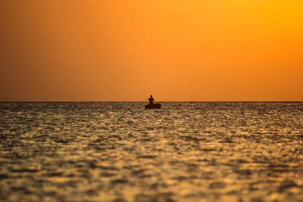 Bateau de pêche dans l'océan sur un fond de coucher de soleil — Photo