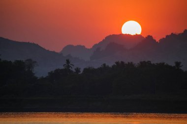 Gün batımının dağların üzerinde olduğu doğal manzara