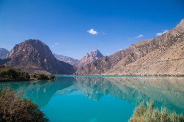 Gün ağarırken Iskanderkul Gölü 'nün ayna yüzeyi dağların arasında.