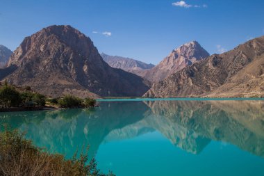 Gün ağarırken Iskanderkul Gölü 'nün ayna yüzeyi dağların arasında.