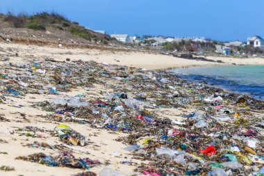 Tropikal bir denizin kumlu sahilinde yakın plan plastik çöpler. Okyanuslardaki ekolojik çöp sorunu